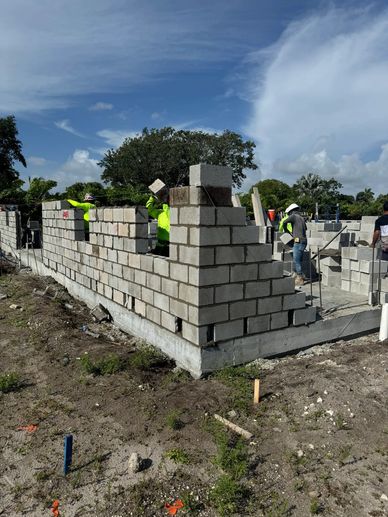 Workers building a concrete block wall.