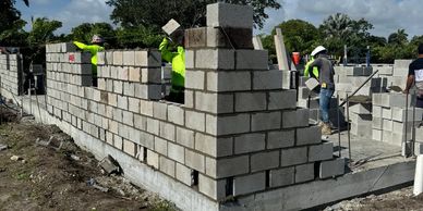 Workers building a concrete block wall.