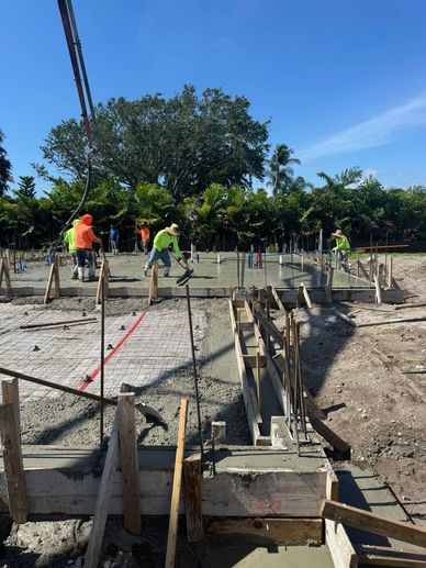 Workers laying concrete slab on construction site.