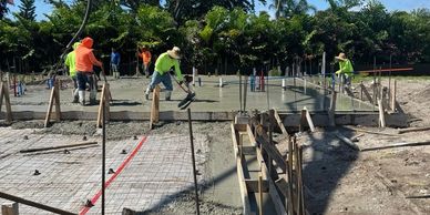 Workers laying concrete slab on construction site.