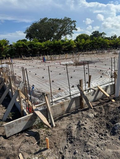 Concrete foundation with rebar and supports at a construction site.