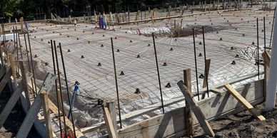 Concrete foundation with rebar and supports at a construction site.