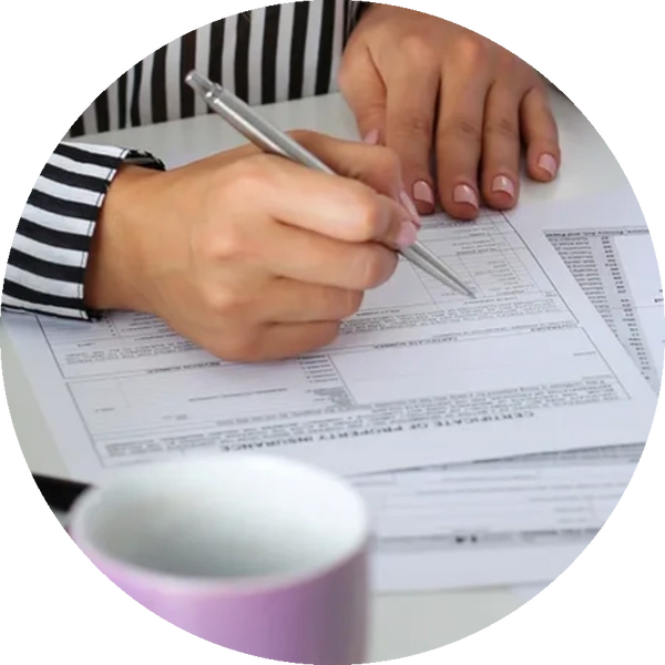 A pair of hands holding a pen preparing medical communications materials. A pink cup in the foregrou