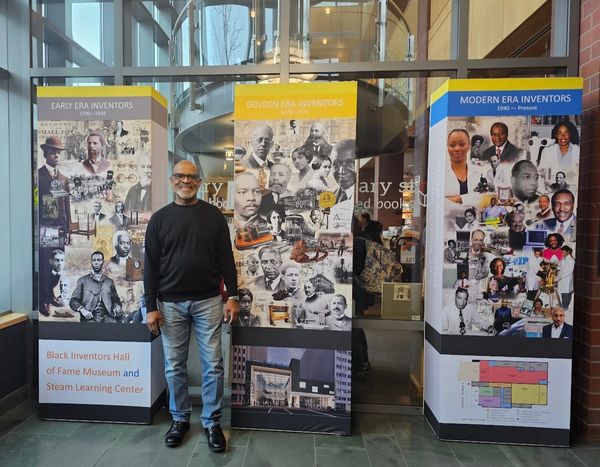 Man standing in front of Black Inventors Hall of Fame museum banners.