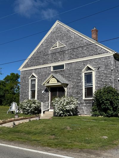 Old wooden building with shingle siding under a clear blue sky.