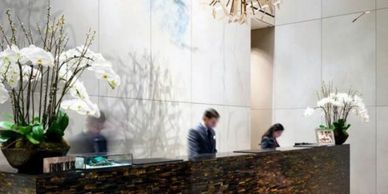 Modern hotel reception desk with staff and elegant orchid arrangements.