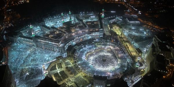 Aerial view of the illuminated Masjid al-Haram during a night gathering.