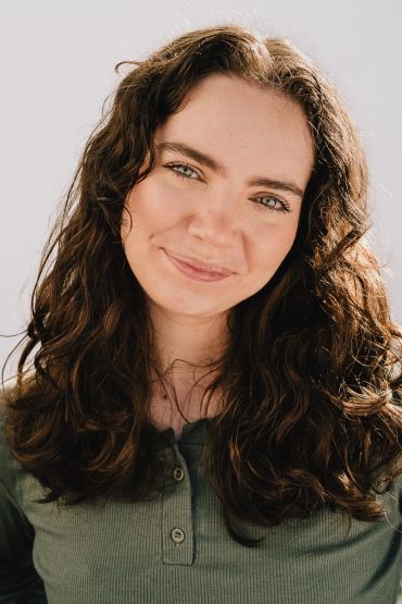 Young woman with curly hair smiling gently.