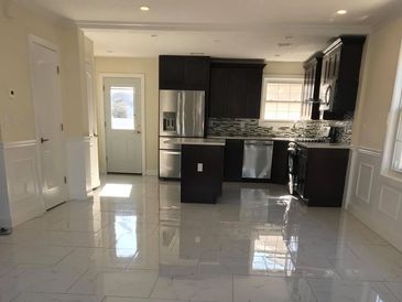 Modern kitchen with dark cabinets and glossy white tiled floor.