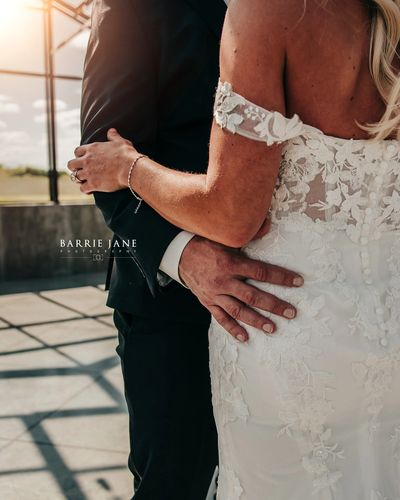 Bride and groom embracing, showing intricate lace wedding dress and suit details.