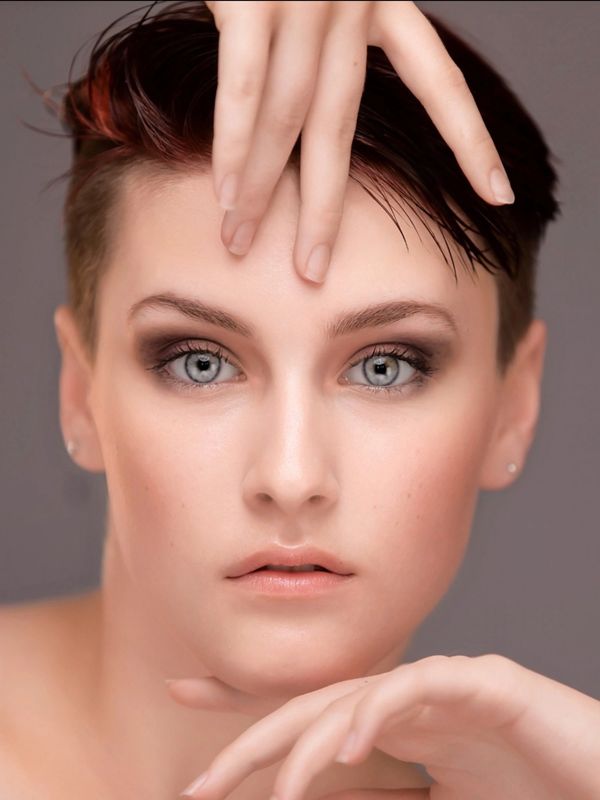 Close-up portrait of a woman with striking blue eyes and short hair.