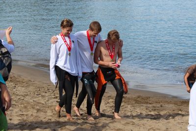 3 Alcatraz swimmers walking up the beach wearing medals around their necks. 