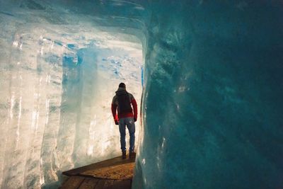 A man approaching the end of a tunnel through ice, seeing the light beyond.