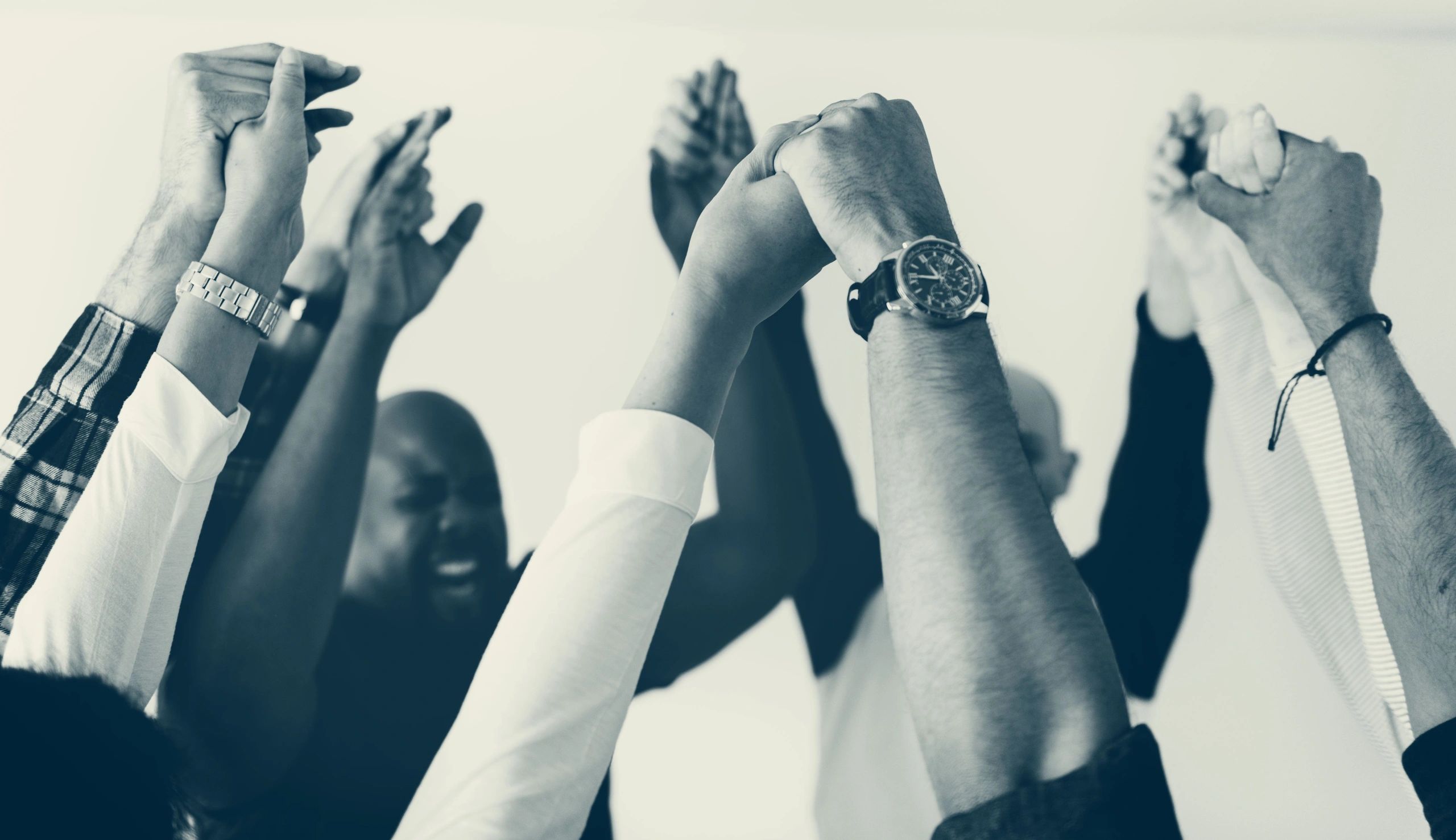 A group of colleagues raising their hands in unity and celebration