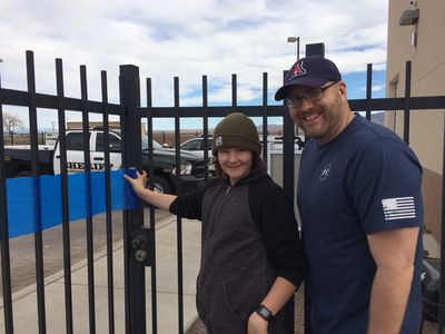 A smiling man and child by a gate.