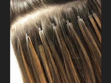 Hair extensions being applied strand by strand.