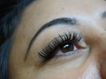 Close-up of an eye with long eyelashes and a well-defined eyebrow.