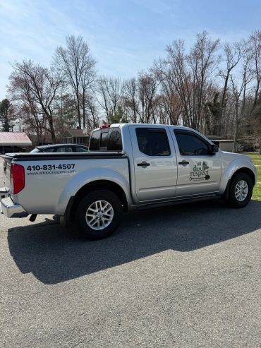 Silver pickup truck with business contact details on the side and back.