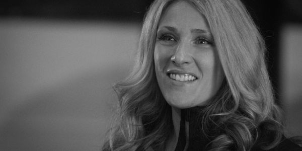 Smiling woman with long wavy hair in black and white.