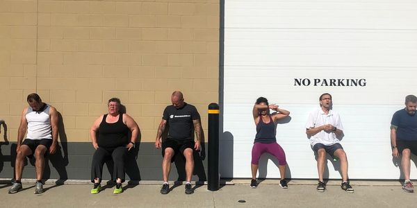 Group exercising against a wall with a 'No Parking' sign.