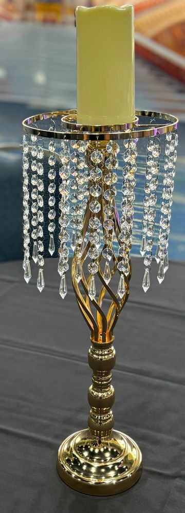 Elegant gold candle holder with hanging crystal beads and a yellow candle.