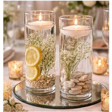 Elegant floating candles in glass vases with flowers and stones.