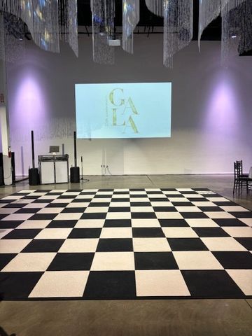 Checkered dance floor with a projection on the wall in a dimly lit venue.