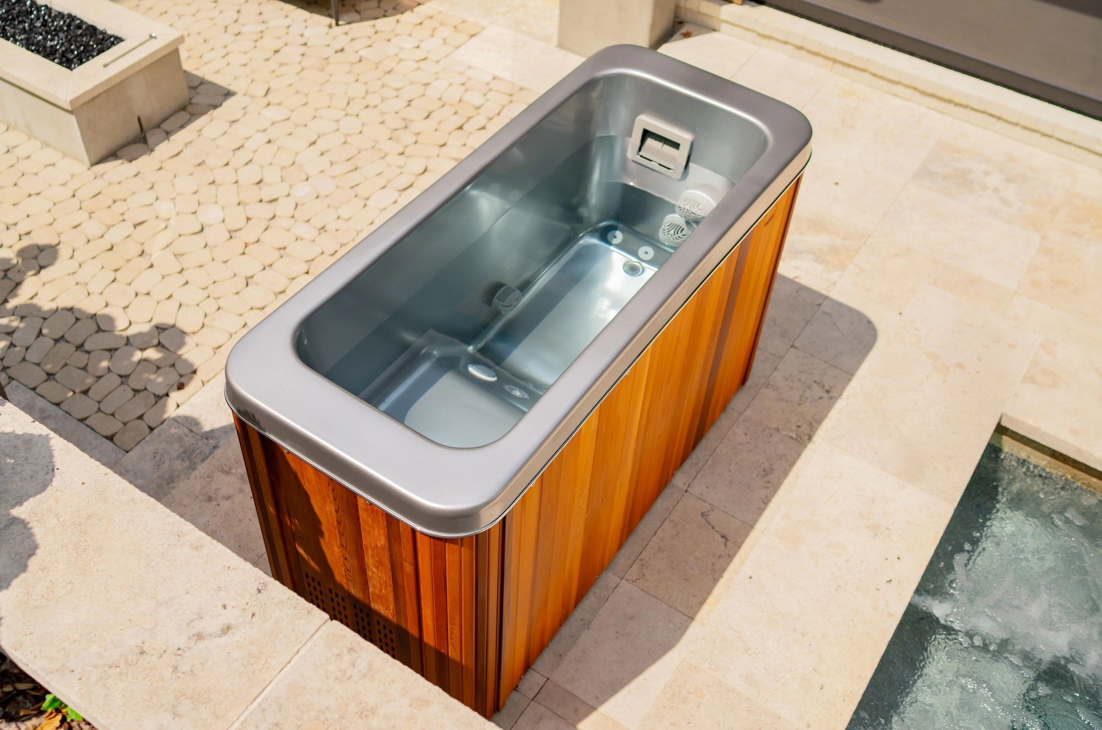 Modern outdoor cold plunge tub with wooden exterior and clear water.