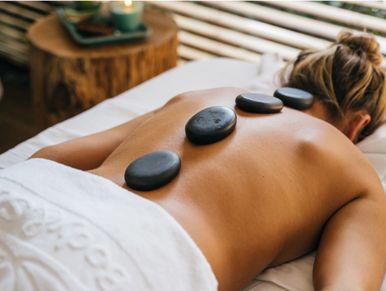 Frau erhält Hot-Stone-Massage auf ihrem Rücken.