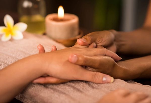 Handmassage in entspannter Atmosphäre mit Kerze.