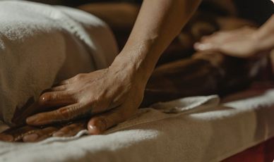 Hand massiert eine Person auf einer Liege.