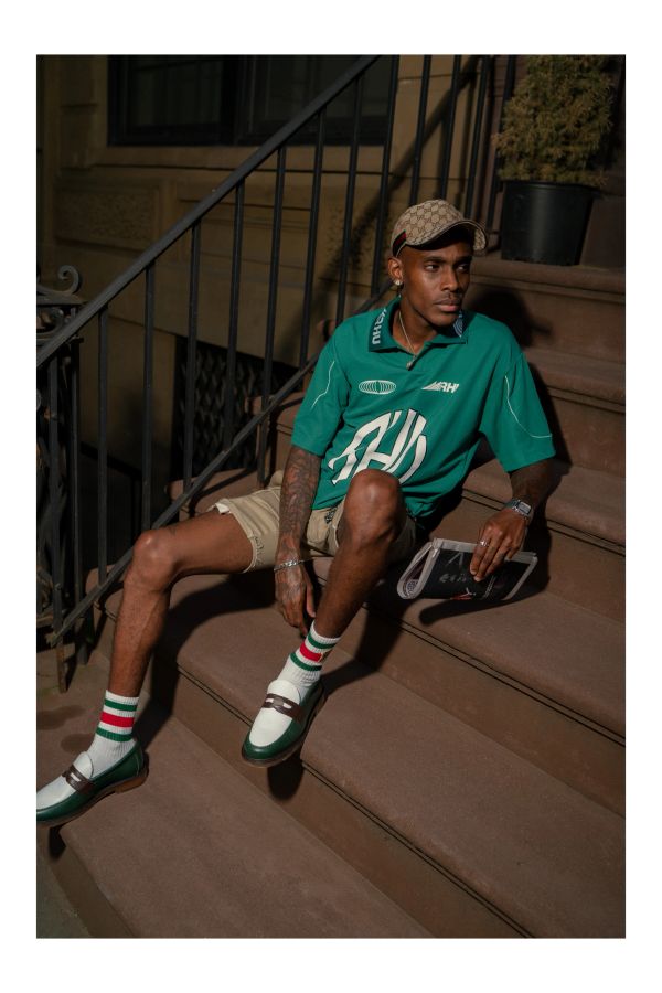 A man sits on brownstone steps, observing the world and life unfolding.