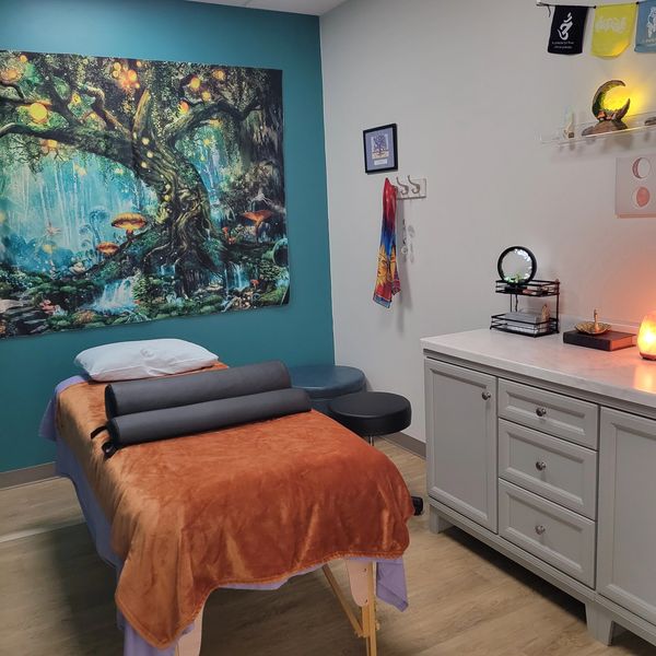 Calm massage room with decorative tapestry and warm lighting.