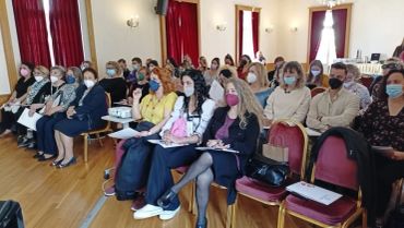 A group of people wearing masks seated in a conference room.