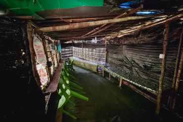 An empty rustic shelter with green plastic chairs.