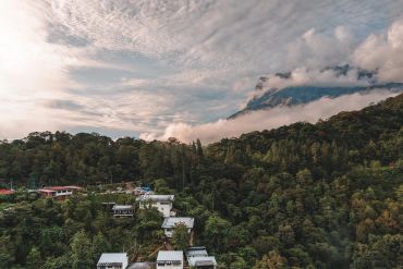 Mountain village nestled in lush green forest under cloudy sky.