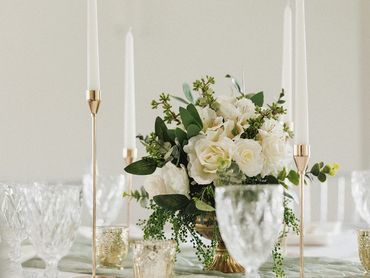 Elegant floral centerpiece with tall white candles on a beautifully set table.