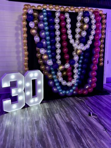 Decorative balloon backdrop with illuminated '30' celebrating a milestone.