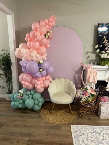 Colorful balloon and floral party decoration with a white chair.