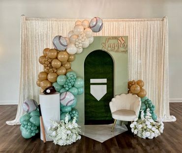 Baseball-themed photo booth setup with balloons and flowers.