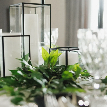 Elegant table setting with candles and green foliage.