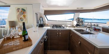 Modern yacht kitchen with wood cabinetry and ocean view windows.