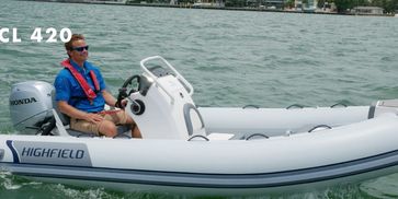 Man driving a white Highfield CL 420 inflatable boat on the water.