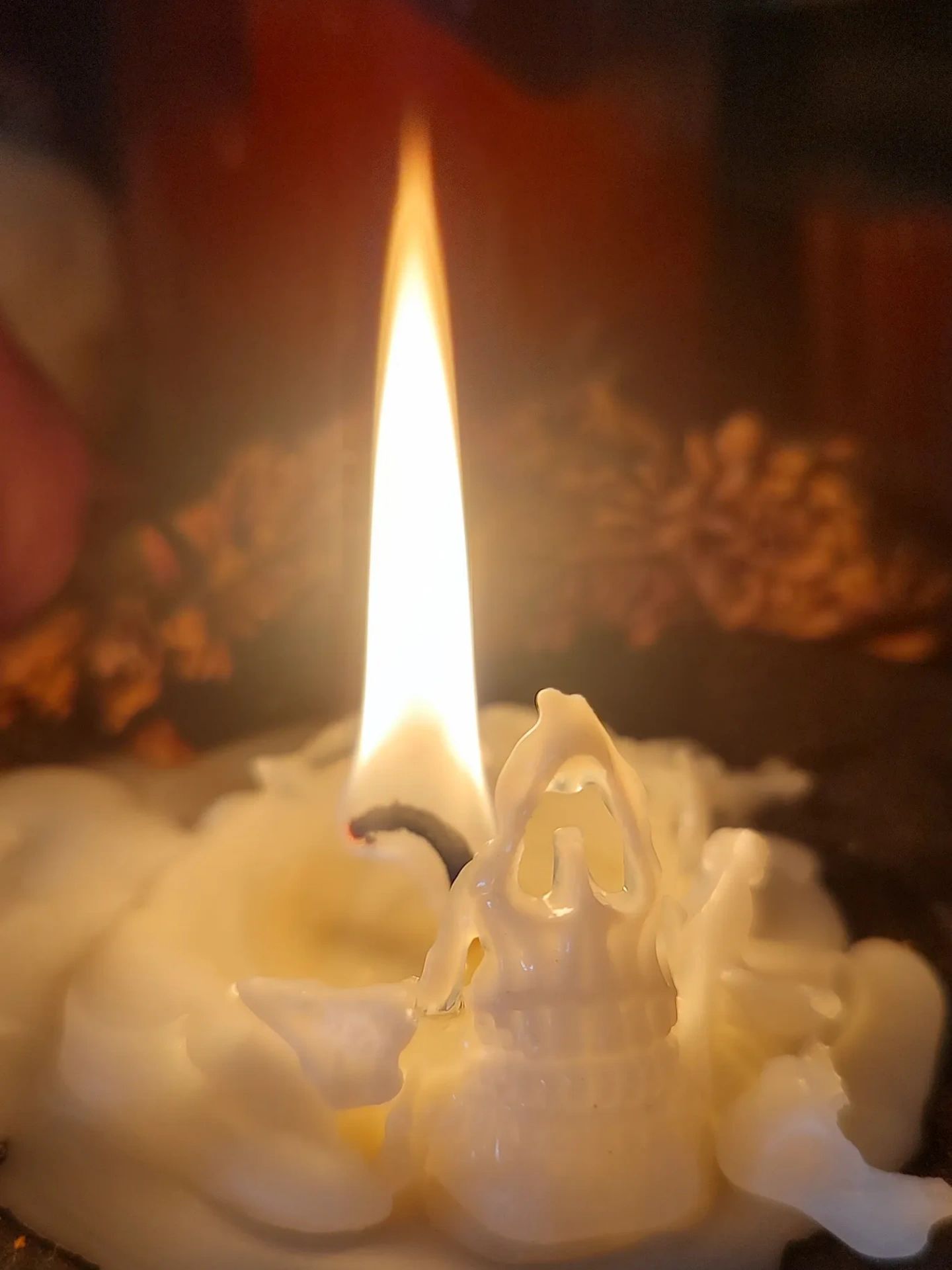 A tall flame inside a puddle of wax