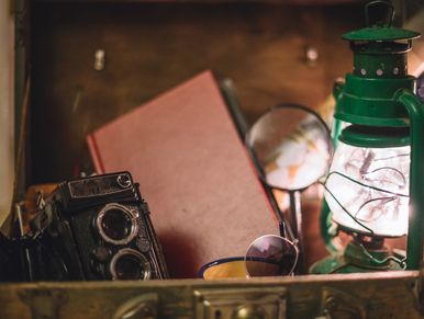 Vintage camera, book, magnifying glass, and lantern in a rustic setting.