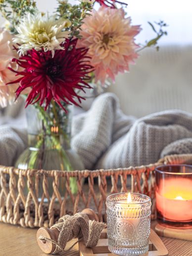 Cozy floral arrangement with lit candles and rustic decor on a wooden surface.