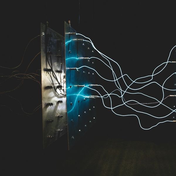 Blue electric wires connected to a panel in a dark setting.