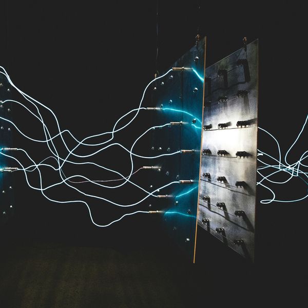 Blue electric wires connected to a panel in a dark setting.