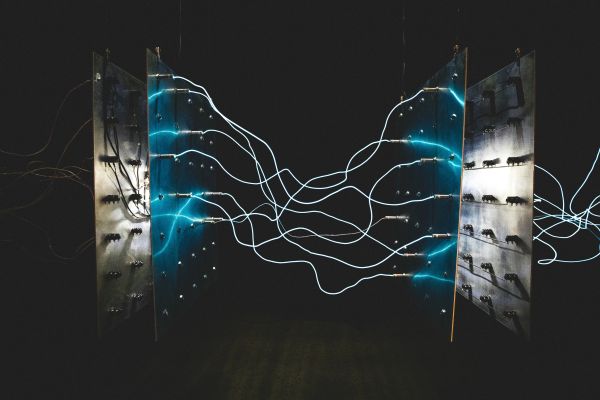 Blue electric wires connected to a panel in a dark setting.