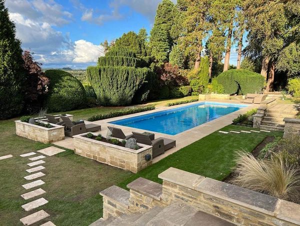 A garden with a luxury swimming pool and surrounding stonework, built by S. Fairless Ltd